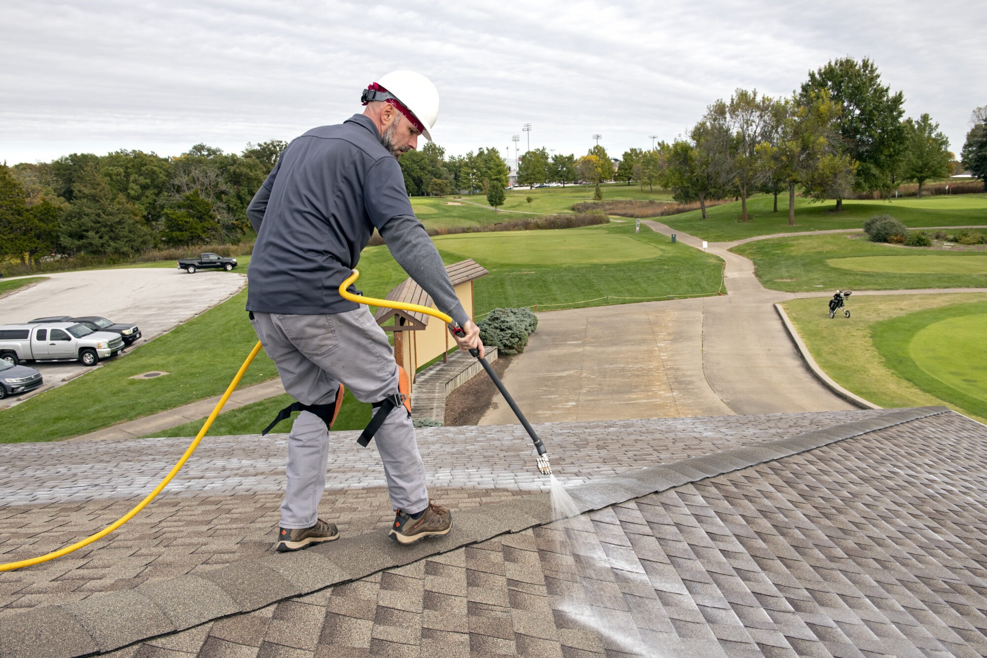 Roof care professional soft washing asphalt shingles from a roof